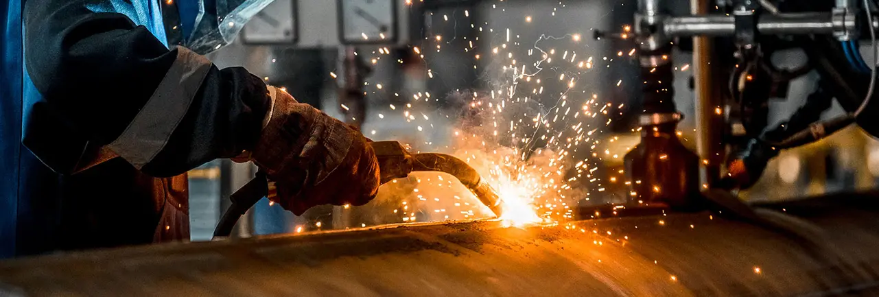 A worker is welding a pellet-producing machine.