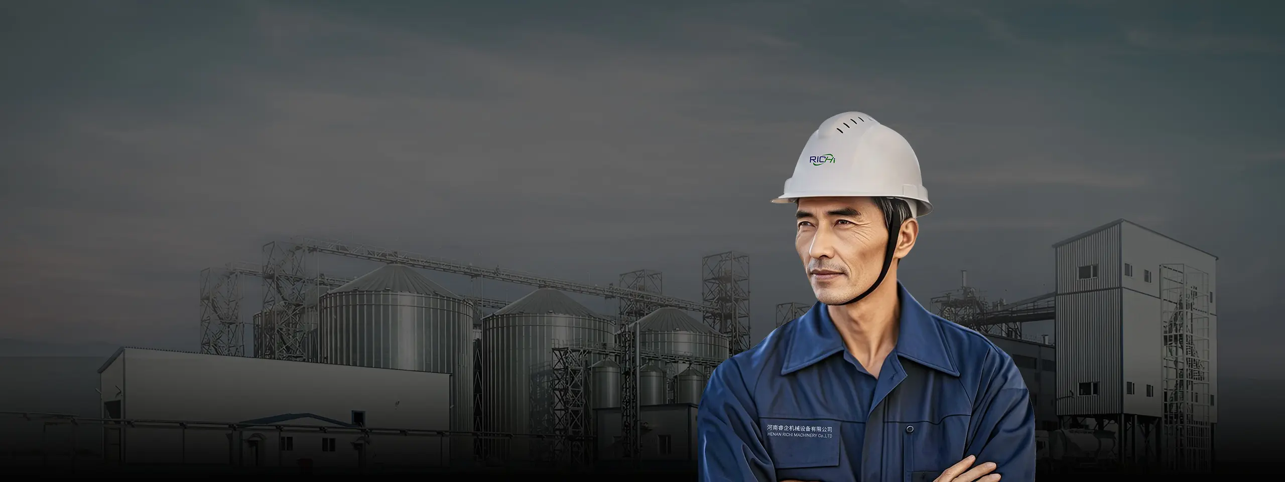 An engineer in a white helmet and a biomass pellet plant in the background.